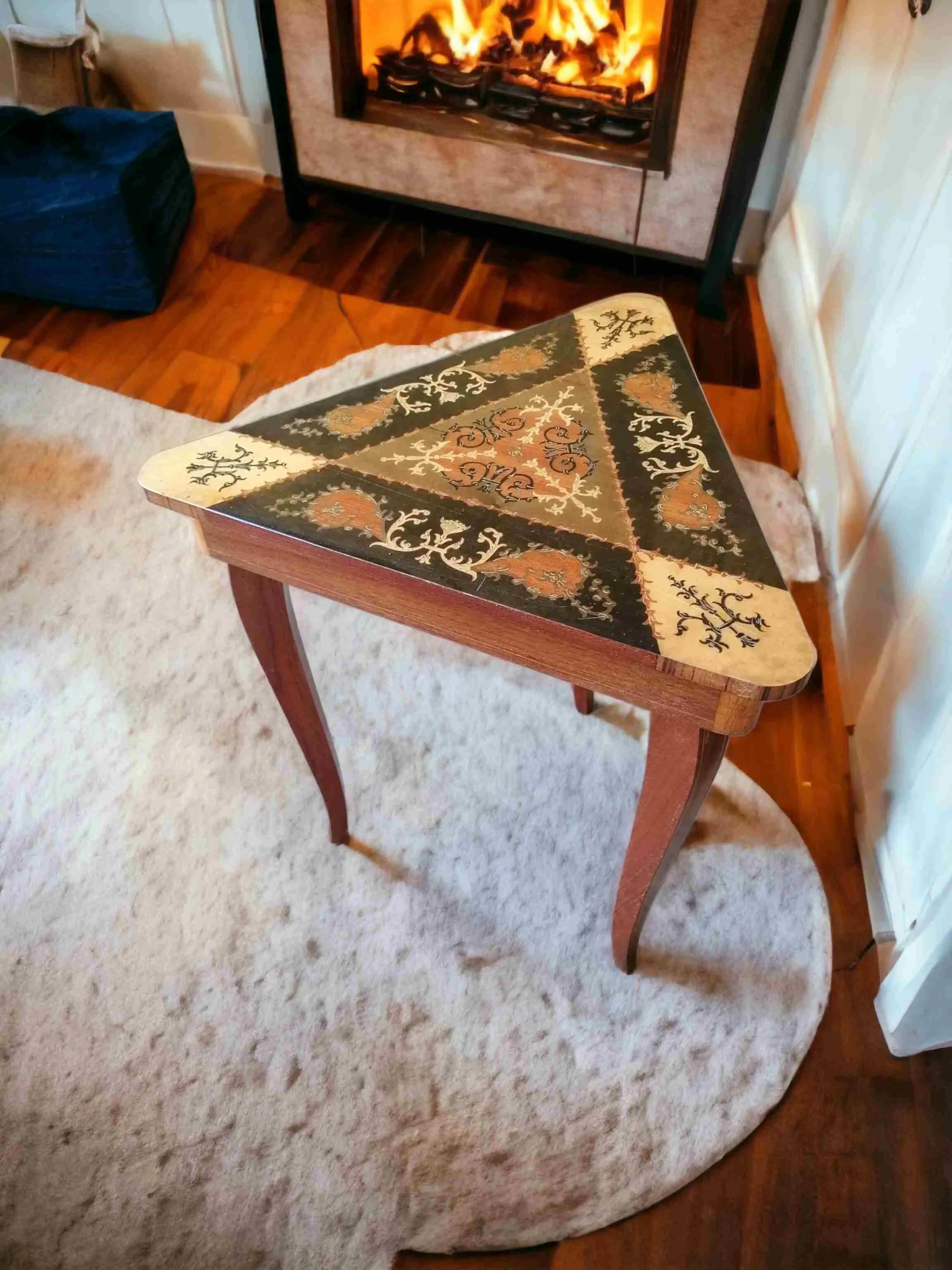 La mesa de joyeros triangular con tapa abatible y Carillón es un mueble refinado y funcional, ideal para añadir un toque de lujo y romanticismo a cualquier ambiente. Esta combinación de elementos prácticos y estéticos crea una pieza única de mobiliario, pensada para quienes buscan un complemento de estilo clásico y atemporal. Características principales: Diseño triangular: La forma no convencional de la mesa la convierte en un punto focal interesante en una habitación, ofreciendo un aspecto elegante y distintivo. Incrustaciones finas: La superficie está decorada con incrustaciones finamente trabajadas, que resaltan la habilidad artesanal y el cuidado de los detalles. Tapa abatible: La funcionalidad de la tapa permite acceder a un compartimento interior donde guardar joyas y pequeños objetos valiosos de manera discreta y segura. Carillón integrado: Completa con Carillón, que agrega un elemento sonoro encantador y nostálgico, otorgando más encanto a la mesa. ¿Por qué elegirla?: Esta mesa es perfecta para quienes buscan un mobiliario que combine elegancia, funcionalidad y un toque de originalidad. La posibilidad de usar la tapa abatible y el Carillón integrado la convierte en una pieza tanto decorativa como práctica, ideal para dormitorios, salas de estar o espacios dedicados al descanso.