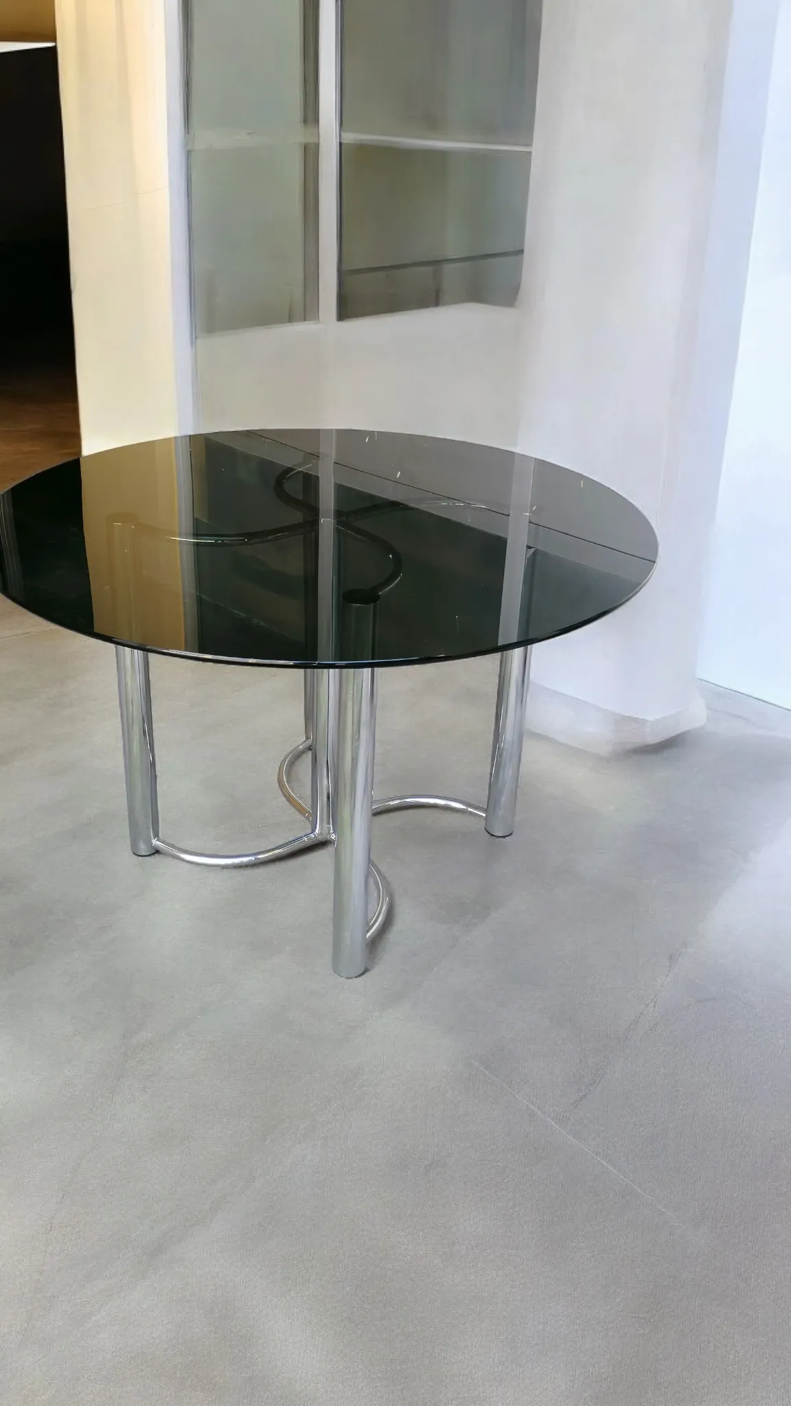 La mesa redonda de acero y vidrio negro atribuida a Giotto Stoppino es un elegante ejemplo de diseño moderno y refinado. Esta creación refleja el estilo distintivo de Stoppino, caracterizado por líneas limpias, minimalismo y un uso innovador de los materiales para crear muebles que combinan estética y funcionalidad. Características principales: Materiales de alta calidad: La base de acero proporciona solidez a la mesa y un aspecto industrial-chic, mientras que el tablero de vidrio negro añade un toque de elegancia y contemporaneidad. Diseño icónico: El estilo de Stoppino se distingue por el equilibrio entre forma y función. Esta mesa redonda es un ejemplo perfecto de su capacidad para hacer muebles prácticos y al mismo tiempo artísticos. Versatilidad: Perfecta para decorar una sala de estar, un comedor o un estudio con un elemento de gran impacto visual. ¿Por qué elegirla?: Esta mesa es ideal para quienes aprecian el diseño italiano de los años 60 y 70, y buscan una pieza que sea el centro del mobiliario. La combinación de acero y vidrio negro ofrece un contraste sofisticado que se integra fácilmente en espacios modernos o eclécticos, elevando la atmósfera del ambiente.