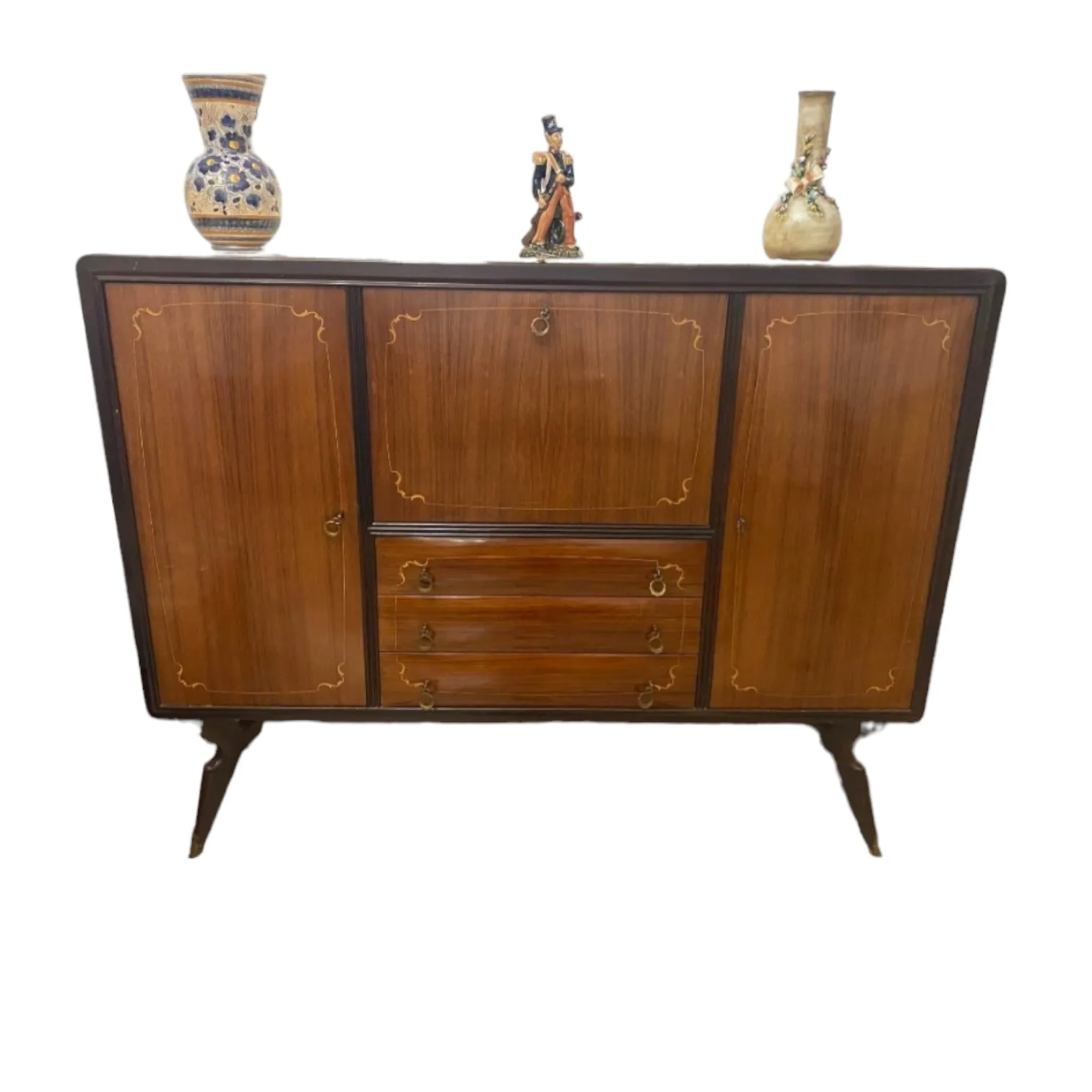 La Credenza Mobile Bar Salon en style Ico Parisi est un meuble fascinant qui allie parfaitement fonctionnalité et esthétique, ce qui la rend parfaite pour des espaces élégants et modernes. Le design de Ico Parisi, connu pour sa capacité à innover tout en préservant l’élégance des formes, se reflète clairement dans cette crédence. Avec une structure minimaliste mais riche en détails raffinés, ce meuble bar est destiné à ceux qui recherchent un meuble sophistiqué qui non seulement répond à des besoins pratiques, mais devient aussi un élément de design distinctif. Caractéristiques principales : Matériau de qualité : La crédence est fabriquée avec des matériaux de haute qualité, comme du bois précieux, traité avec des finitions brillantes pour un aspect élégant et contemporain. Design fonctionnel et stylé : Grâce à ses lignes épurées, ses courbes modernes et l’introduction de détails en métal ou en verre, le style Ico Parisi est parfaitement représenté dans ce meuble. Le meuble bar est composé de sections spacieuses pour contenir des bouteilles, des verres et des accessoires de bar, tout en conservant un aspect léger et aéré. Polyvalence d’utilisation : En plus d’être un meuble bar pratique, cette crédence peut également servir de point de référence central dans le salon, ajoutant une touche de classe au séjour. Pourquoi la choisir : La Credenza Mobile Bar en style Ico Parisi est idéale pour les amateurs de design vintage et moderne qui apprécient l’élégance et la praticité dans un seul meuble. Sa capacité à mêler design innovant et fonctionnalité en fait un meuble parfait pour aménager des salons, des séjours et même des espaces ouverts, où le meuble bar devient le centre d’attention. Grâce à sa polyvalence, il peut s’adapter à différents styles de décoration, offrant une sensation de luxe et de modernité.