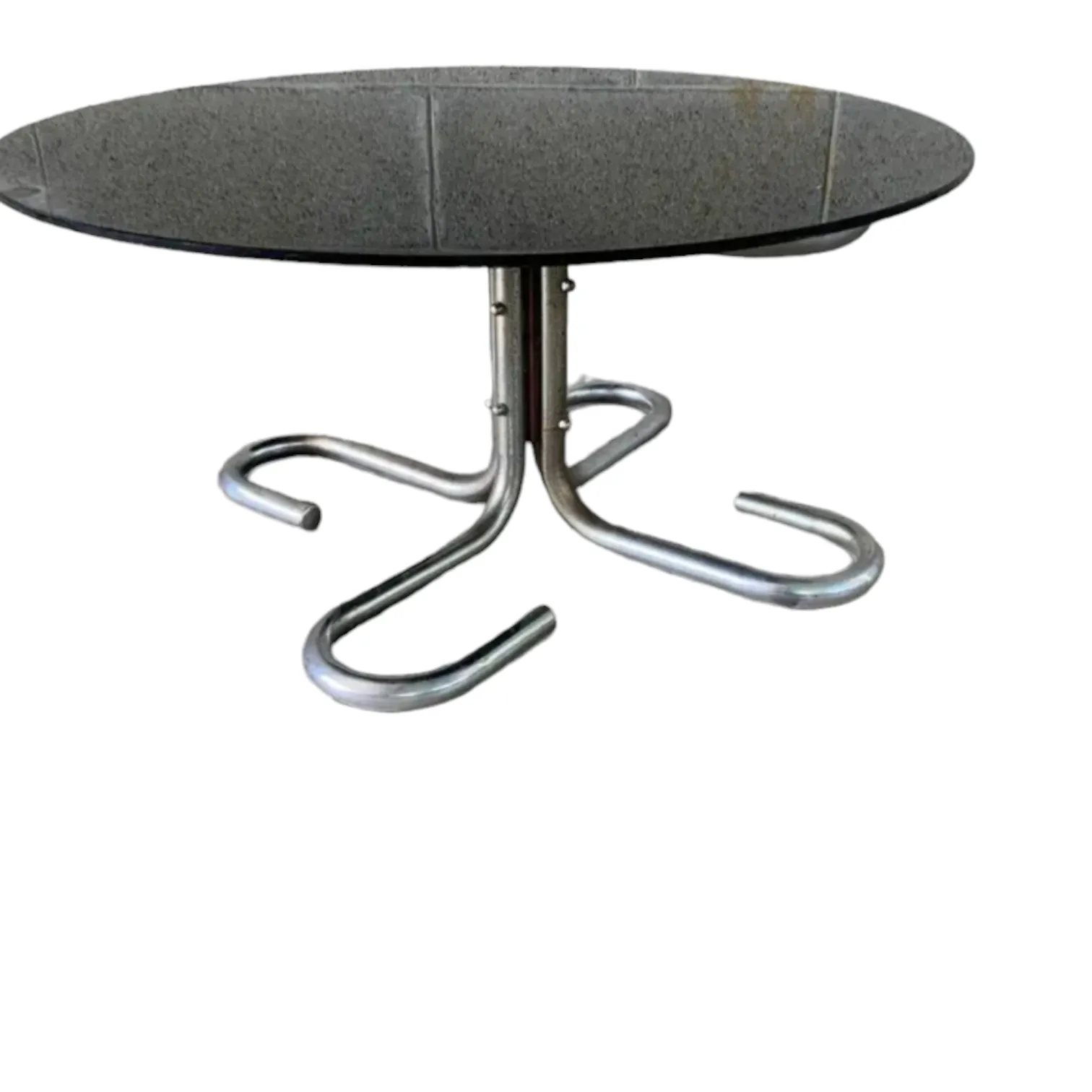 La mesa baja de salón con estructura cromada y tablero de vidrio redondo ahumado de Giotto Stoppino es un ejemplo icónico del diseño italiano de los años 60, que fusiona elegancia, minimalismo y funcionalidad en un objeto de gran impacto visual. Giotto Stoppino, conocido por su capacidad para combinar materiales y formas de manera innovadora, creó una mesa que se convierte en el centro de cualquier ambiente moderno. Características principales: Estructura cromada: La base en metal cromado le da a la mesa un aspecto brillante y moderno, capaz de reflejar la luz y adaptarse perfectamente a espacios luminosos y contemporáneos. Tablero de vidrio ahumado: El vidrio ahumado, con su color difuso y su superficie transparente, añade un toque sofisticado y misterioso. Este tablero de vidrio redondo no solo es práctico, sino también un elemento decorativo que se adapta perfectamente a la estética minimalista del diseño. Diseño minimalista: La mesa de Stoppino es un ejemplo de cómo el uso de pocos elementos y líneas limpias puede generar un fuerte impacto estético, convirtiéndola en una pieza versátil para cualquier tipo de decoración moderna. ¿Por qué elegirla?: Esta mesa es perfecta para quienes aprecian el diseño sofisticado y atemporal. Adecuada para salones, oficinas o espacios de entretenimiento, ofrece funcionalidad y refinamiento con su apariencia minimalista y líneas elegantes. Es un objeto que, en su simplicidad, se convierte en el centro de atención de un ambiente, gracias a su estética refinada y su diseño innovador. Ideal para quienes aman el mobiliario de alta calidad, con un toque de clase discreta.