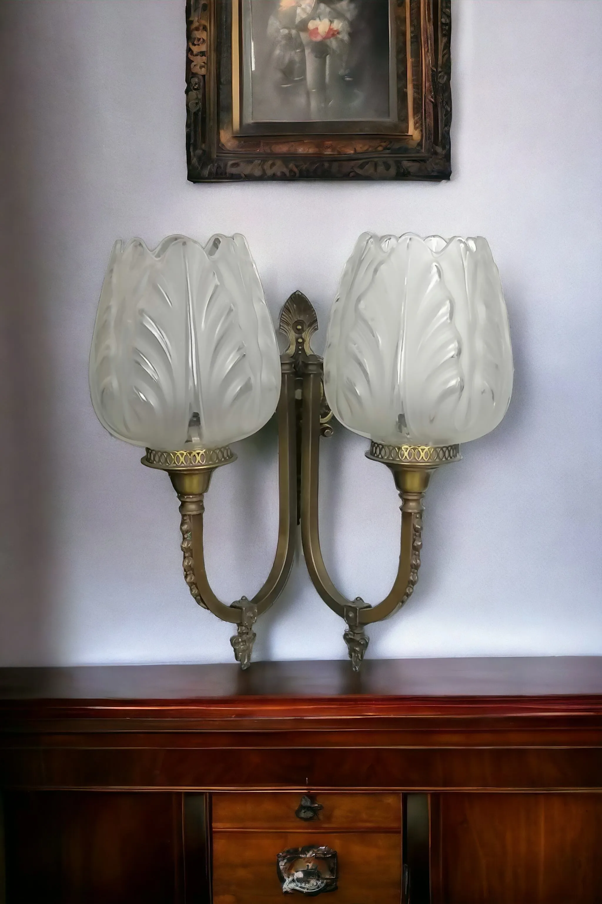 Les appliques en laiton à deux bras avec points lumineux en forme de tulipe sont un choix décoratif élégant et polyvalent. Ce design est souvent associé à des styles classiques ou Art Nouveau, où la forme de la tulipe est un élément récurrent pour évoquer la beauté de la nature. Caractéristiques principales : Laiton : Le laiton donne une couleur chaude et une brillance raffinée. Il peut être laissé brillant pour un aspect plus contemporain ou patiné pour un effet vintage. Le laiton est durable et résistant, idéal pour les structures des appliques. Forme de tulipe : Les points lumineux en forme de tulipe sont souvent réalisés en verre opalin, verre satiné ou albâtre, pour diffuser une lumière douce et uniforme. Cette forme ajoute une touche florale et délicate à l’applique, la rendant parfaite pour des espaces accueillants comme les chambres à coucher, les salons ou les couloirs. Style : Ce design s’adapte bien à des contextes à la fois classiques et modernes, et évoque une esthétique romantique et naturelle. Les styles Art Nouveau ou Liberty, en particulier, célèbrent des lignes organiques et des motifs floraux, que l’on retrouve dans ces formes de tulipes. Si vous souhaitez valoriser ces appliques, envisagez de les associer à des murs aux tons chauds ou à des décorations en bois, marbre ou autres matériaux naturels. De plus, la lumière tamisée des points lumineux en forme de tulipe peut créer une ambiance intime, idéale pour des coins lecture ou pour apporter une touche de classe aux entrées et couloirs.