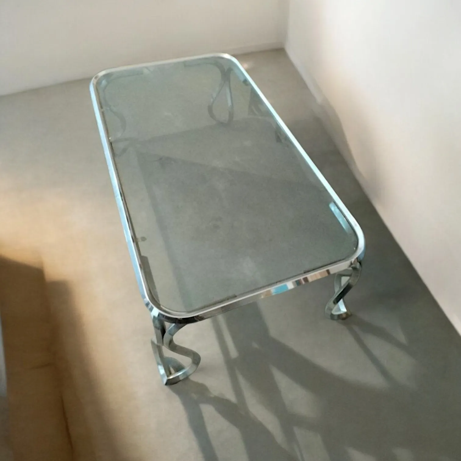 La mesa baja de metal cromado con tapa de vidrio ahumado es una elegante pieza de mobiliario que combina funcionalidad y diseño moderno. Caracterizada por su estructura de metal cromado brillante y su tapa de vidrio ahumado, esta mesa encaja perfectamente en ambientes de gusto contemporáneo, enriqueciendo el espacio con un toque de sofisticación. El vidrio ahumado da un aspecto sofisticado y ligeramente misterioso, mientras que la base de metal cromado aporta luminosidad y contraste. Características principales: Estructura de metal cromado: Brillante y moderna, esta base otorga estabilidad y durabilidad a la mesa, siendo ideal para ambientes de estilo industrial o minimalista. Tapa de vidrio ahumado: La transparencia del vidrio, junto con su color difuso, crea una sensación de ligereza, lo que permite que la mesa se integre fácilmente con otros muebles sin sobrecargar el espacio. Diseño elegante y versátil: Con su estilo sobrio y atemporal, la mesa es perfecta para usarse en salas de estar, oficinas o salas de lectura, donde puede funcionar tanto como un objeto decorativo como una superficie funcional. Por qué elegirla: Esta mesa baja de metal cromado con tapa de vidrio ahumado es la elección perfecta para quienes buscan un mueble de diseño moderno pero con una elegancia discreta. Es ideal para espacios de estilo contemporáneo, donde la funcionalidad y la estética se encuentran para crear un ambiente armonioso y refinado. Con su estructura sólida y su tapa de vidrio, es el complemento ideal para enriquecer cualquier habitación con un toque de clase.