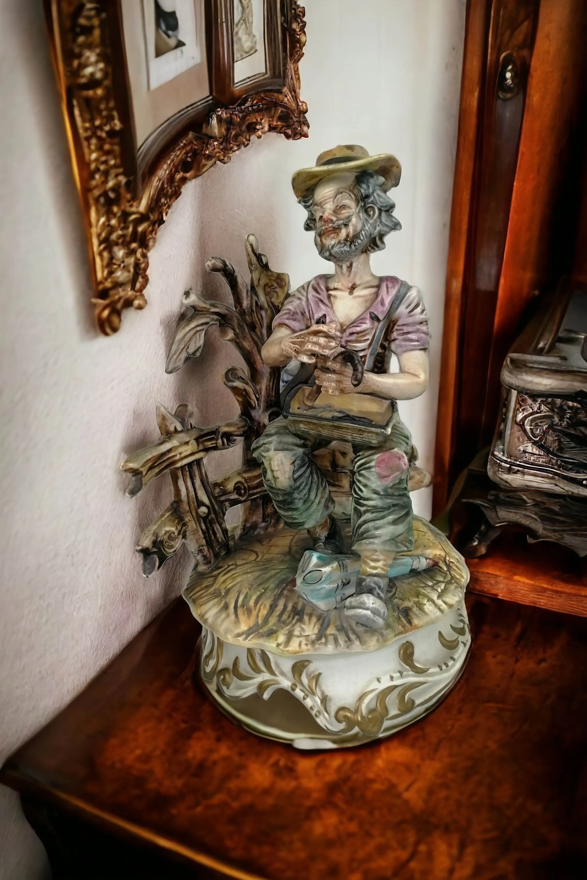 Capodimonte的“老人与破伞”雕像是一件迷人的作品，展示了一个日常生活场景，带有典型的Capodimonte制造风格的优雅。雕刻得非常精美的老人手持一把破伞，表现出智慧与宁静的表情，这些都是此类人物的典型特征。材料与工艺：像所有Capodimonte的陶瓷一样，这尊雕像采用最高质量的瓷器制作，细节非常精致，从老人的面部和手部到衣服的褶皱，甚至是伞的纹理。光滑或哑光的表面处理突显了材料的美感，使雕像呈现出精致和宝贵的外观。设计与细节：这尊雕像的设计充满了吸引人的细节。老人稳稳地握住伞柄，姿势传达出宁静与沉思的感觉。伞本身也雕刻得非常详细，准确地再现了布料的褶皱和伞骨。老人的面部表情通常是宁静的，进一步增加了雕像的独特魅力。象征意义：这尊“破伞老人”可以被看作是时间流逝的隐喻，伞象征着对外界世界的保护，是孤独、经验与智慧的反思。老人的形象，通常是宁静与成熟的象征，与伞的保护象征相契合，提供了庇护和保护。理想的摆放位置：这尊雕像非常适合经典而精致的环境，如客厅、书房或图书馆。它也可以作为展示柜或架子上的装饰元素，成为引起好奇与欣赏的焦点。此外，由于其永恒的优雅，适合展示在庆祝陶瓷艺术传统的空间中。为什么选择“破伞老人”雕像？Capodimonte的“破伞老人”雕像是寻找一件融合质量、优雅与象征意义的艺术品的理想选择。每一件Capodimonte签名的作品都是手工艺传统与艺术技艺的融合，而这一主题的雕像，以其细腻与象征意义，完美适合那些想要为家中增添一份精致感的人。 